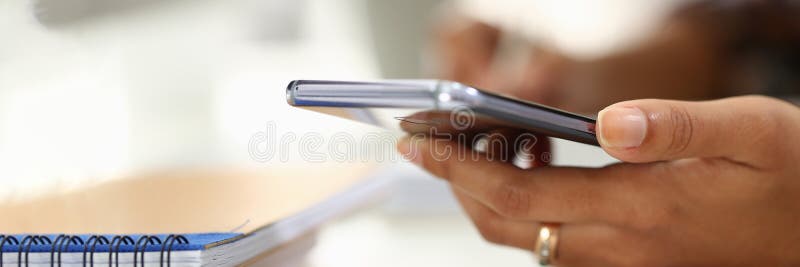 Student writes in notebook and holds smartphone. Woman hands taking notes using online organizer app on mobile phone concept. Student writes in notebook and holds smartphone. Woman hands taking notes using online organizer app on mobile phone concept