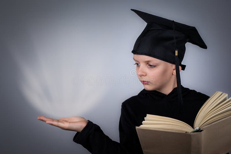 Student or pupil with black graduate hat reading opened shool book