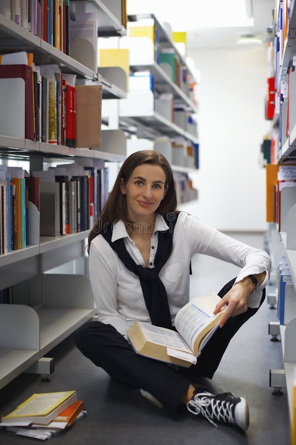 Student sitting between bookshelves reading