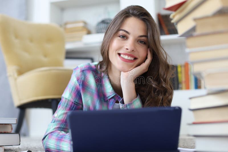 Student studying at home, sitting on floor using tablet against cozy domestic interior, surrounded with pile of books royalty free stock photography Student studying at home, sitting on floor using tablet against cozy domestic interior, surrounded with pile of books royalty free stock photography