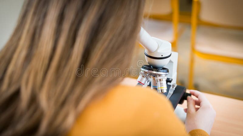 Student using microscope to examine samples in biology class.