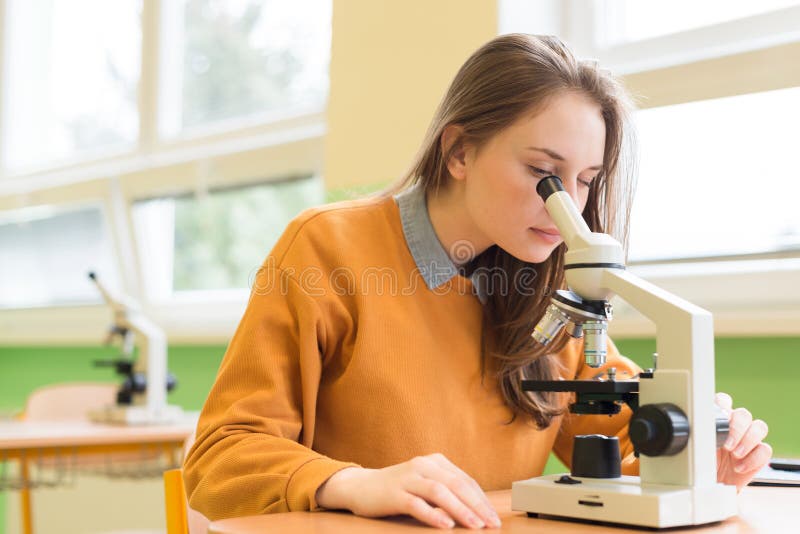 Student using microscope to examine samples in biology class.