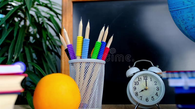Studentbord med vita larmklockböcker med orangefärgade bärbara datorer pennor i glaspärlbord, vitt