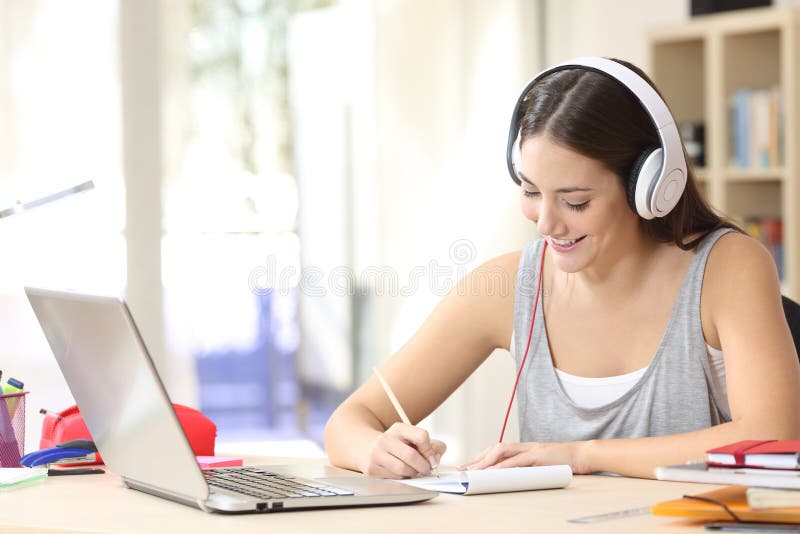 Studente che impara con le cuffie che prendono le note immagini stock Studente che impara con le cuffie che prendono le note immagini stock