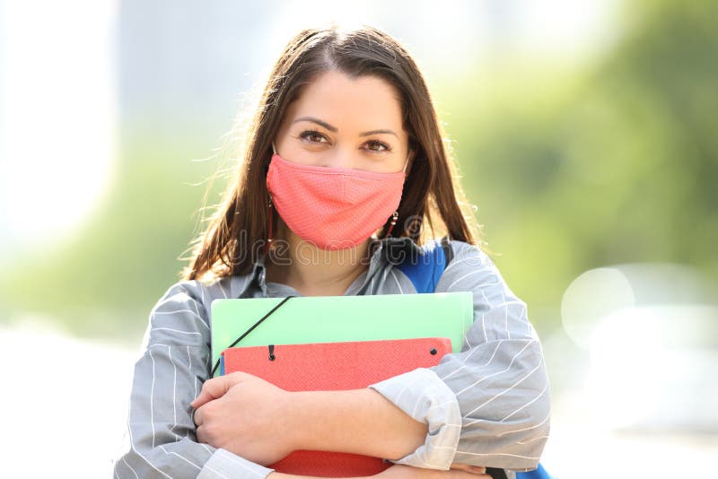 Studente felice con la maschera che pone in strada immagini stock