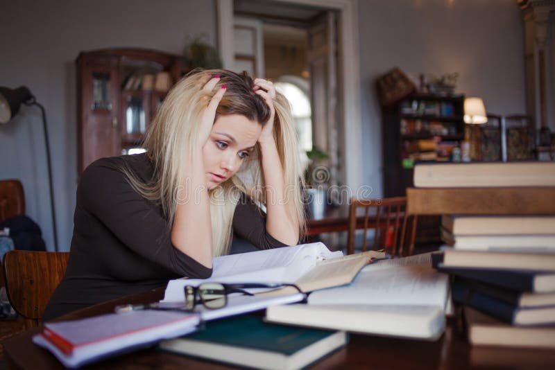 Studente stanco della giovane donna dell'università Preparando esame ed apprendimento delle lezioni in biblioteca pubblica immagini stock Studente stanco della giovane donna dell'università Preparando esame ed apprendimento delle lezioni in biblioteca pubblica immagini stock