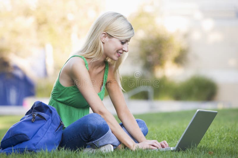 Studente universitario che per mezzo del computer portatile all'esterno fotografie stock Studente universitario che per mezzo del computer portatile all'esterno fotografie stock