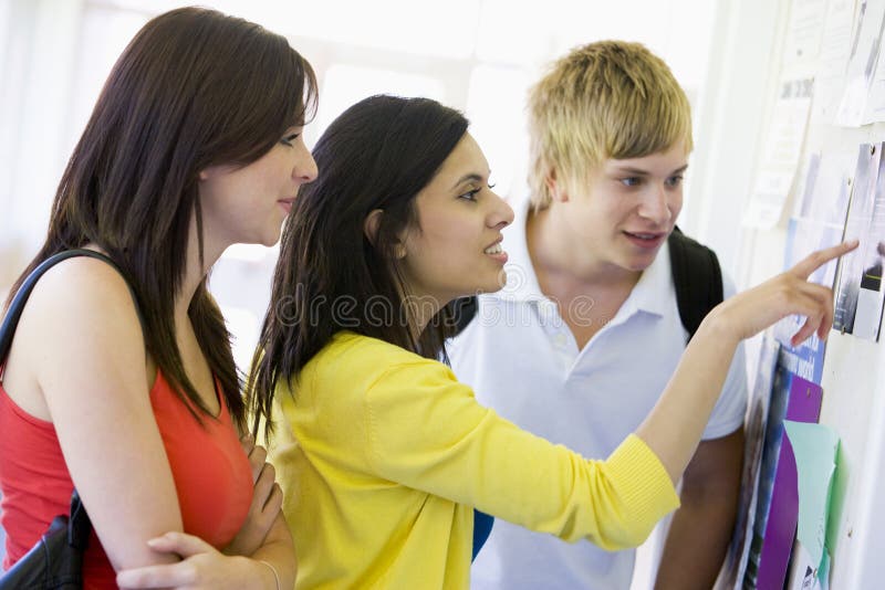 Studenten, die ein Anschlagbrett betrachten lizenzfreies stockbild Studenten, die ein Anschlagbrett betrachten lizenzfreies stockbild