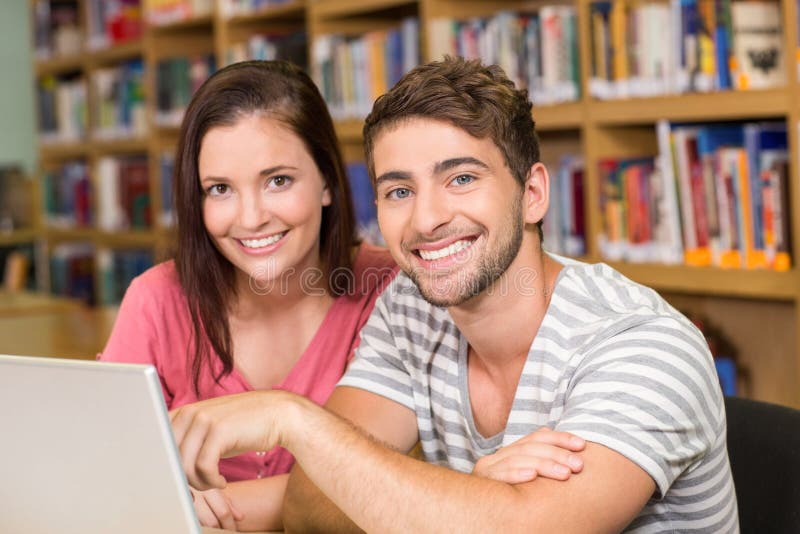 Studenten, die Laptop in der Bibliothek verwenden lizenzfreie stockfotografie Studenten, die Laptop in der Bibliothek verwenden lizenzfreie stockfotografie