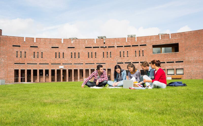 Studenten, die Laptop im Rasen gegen Collegegebäude verwenden stockfoto Studenten, die Laptop im Rasen gegen Collegegebäude verwenden stockfoto