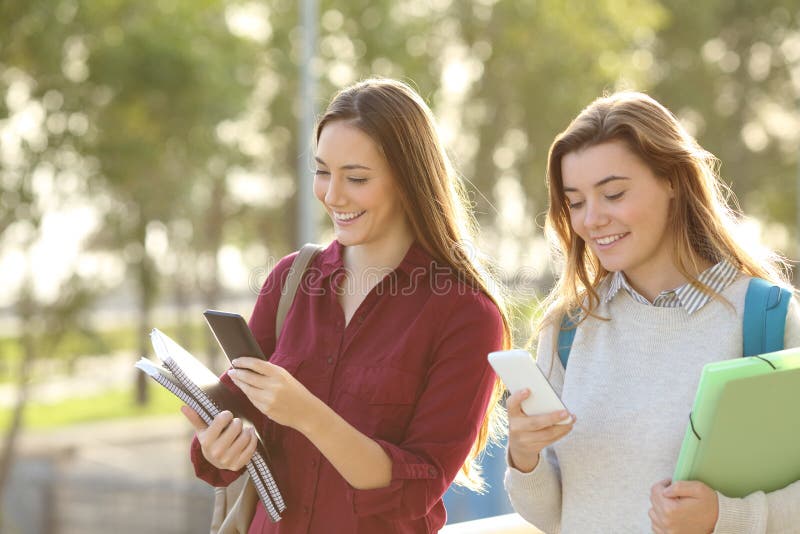 Studenten, die mit intelligenten Telefonen gehen lizenzfreies stockbild Studenten, die mit intelligenten Telefonen gehen lizenzfreies stockbild