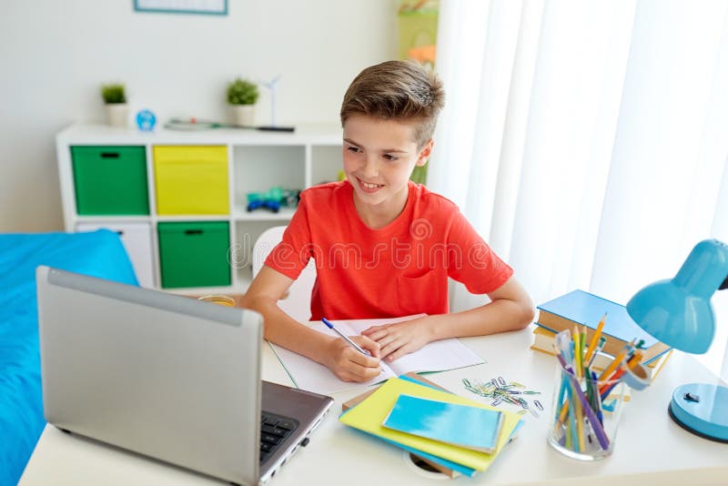 Studentenjongen die met laptop aan notitieboekje schrijven royalty-vrije stock afbeeldingen Studentenjongen die met laptop aan notitieboekje schrijven royalty-vrije stock afbeeldingen