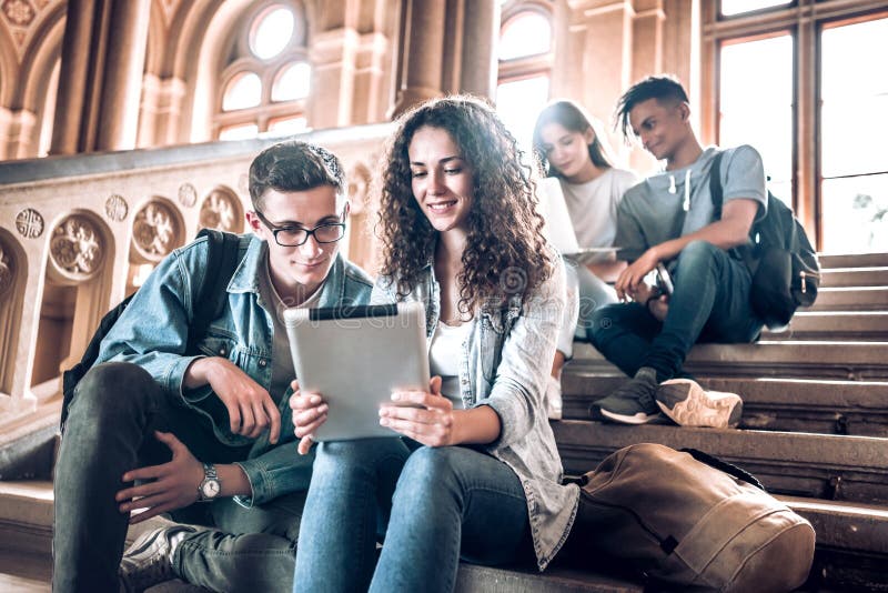 Studentenleben Gruppe Studenten, die eine Tablette beim Sitzen auf Treppe in der Universität verwenden lizenzfreie stockbilder Studentenleben Gruppe Studenten, die eine Tablette beim Sitzen auf Treppe in der Universität verwenden lizenzfreie stockbilder