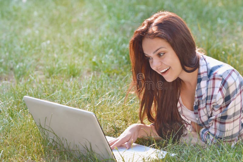 Studentenmeisje die aan laptop werken die op gras in park liggen royalty-vrije stock foto's Studentenmeisje die aan laptop werken die op gras in park liggen royalty-vrije stock foto's