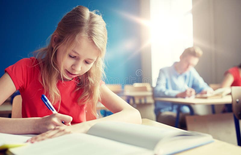Studentenmeisje met boek het schrijven schooltest royalty-vrije stock foto Studentenmeisje met boek het schrijven schooltest royalty-vrije stock foto