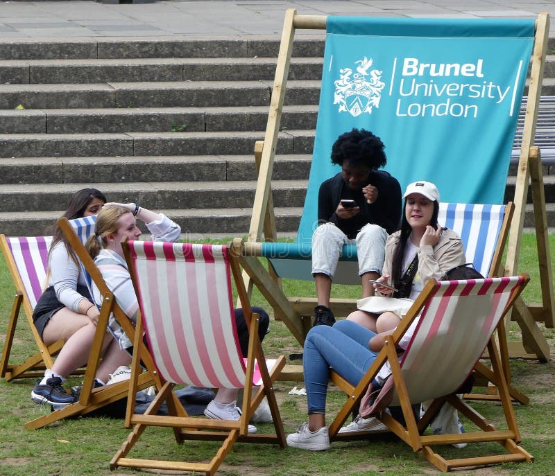 Studenter som kopplar av på solstolar på det Brunel universitetet London royaltyfri fotografi Studenter som kopplar av på solstolar på det Brunel universitetet London royaltyfri fotografi