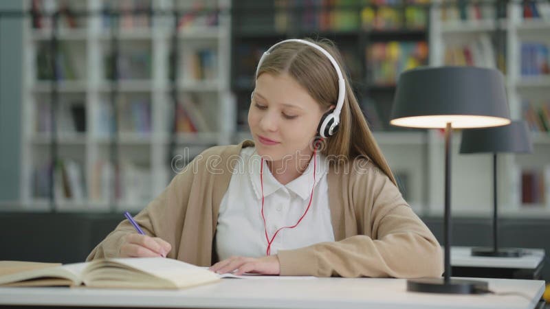 Studentessa che fa i compiti e ascolta musica con le cuffie