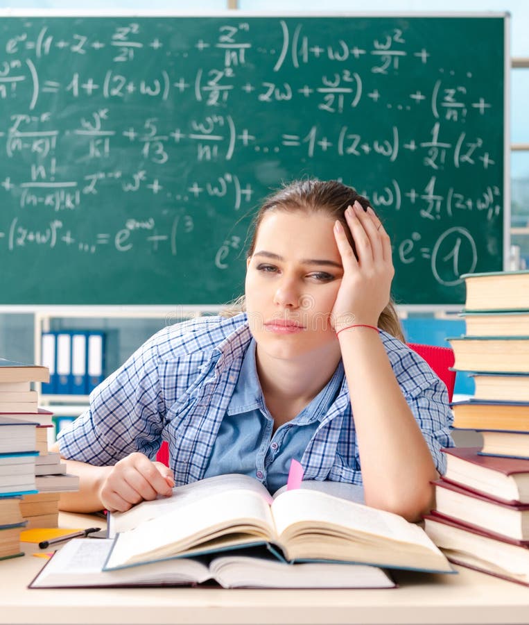 Studentessa con molti libri seduti in classe fotografia stock