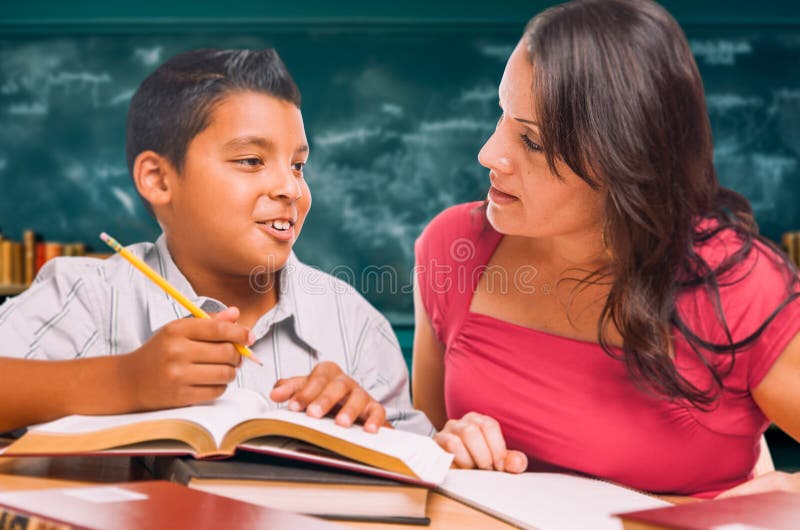 Studentessa di scuola fa i compiti con un giovane ispanico in classe immagine stock