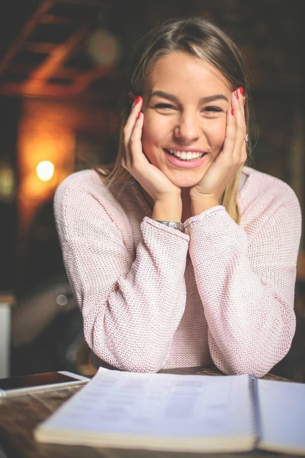 Studentessa felice sorridente che impara e che esamina macchina fotografica immagini stock libere da diritti Studentessa felice sorridente che impara e che esamina macchina fotografica immagini stock libere da diritti