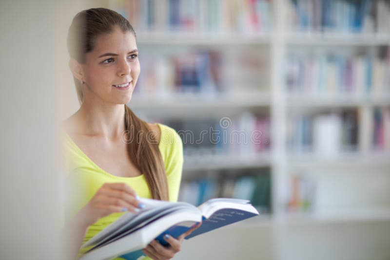 Studentessa universitaria carina con libri in biblioteca