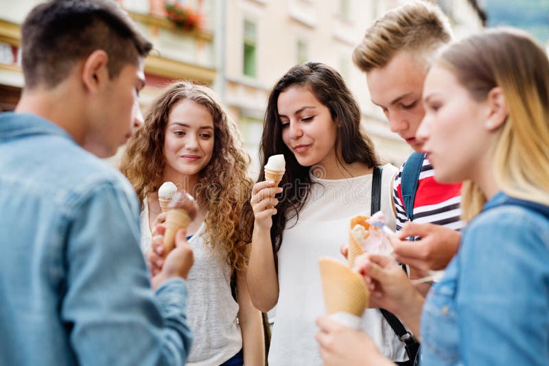 Studenti adolescenti attraenti in città che mangiano il gelato fotografie stock Studenti adolescenti attraenti in città che mangiano il gelato fotografie stock
