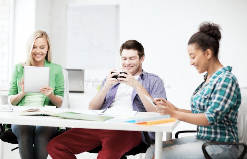 Studenti che esaminano i dispositivi alla scuola immagine stock Studenti che esaminano i dispositivi alla scuola immagine stock