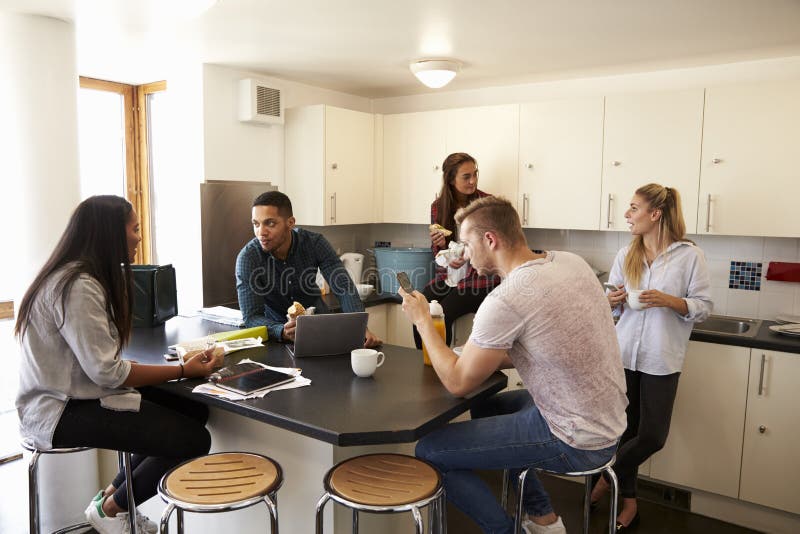 Students Relaxing In Kitchen Of Shared Accommodation. Students Relaxing In Kitchen Of Shared Accommodation