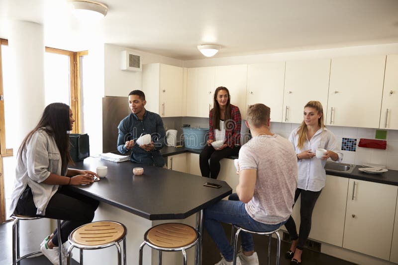 Students Relaxing In Kitchen Of Shared Accommodation. Students Relaxing In Kitchen Of Shared Accommodation