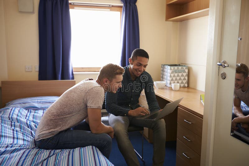 Male Students Working In Bedroom Of Campus Accommodation. Male Students Working In Bedroom Of Campus Accommodation