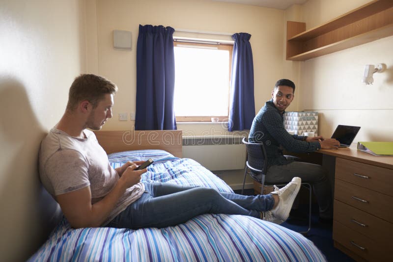 Male Students Working In Bedroom Of Campus Accommodation. Male Students Working In Bedroom Of Campus Accommodation