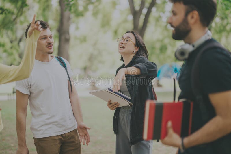 Studenti multiculturali che collaborano all'aperto a progetti scolastici dopo le lezioni fotografia stock