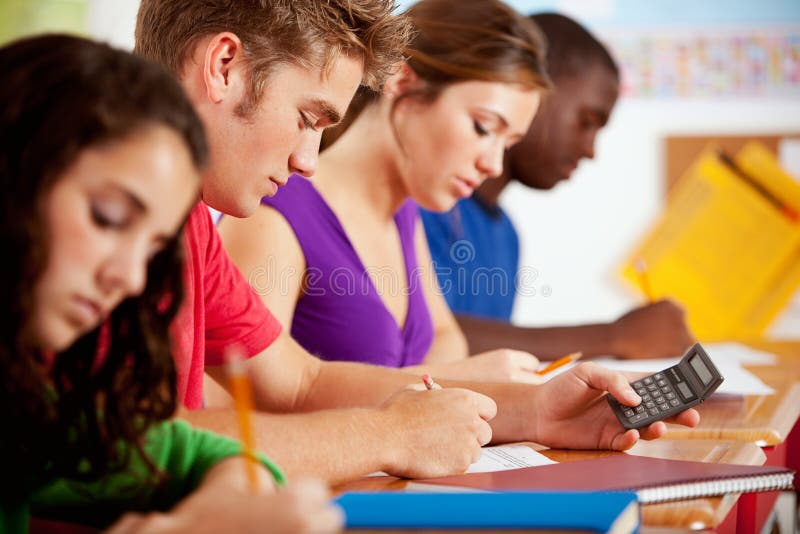Studenti: Teenager maschio astuto facendo uso del calcolatore per compito immagini stock libere da diritti Studenti: Teenager maschio astuto facendo uso del calcolatore per compito immagini stock libere da diritti