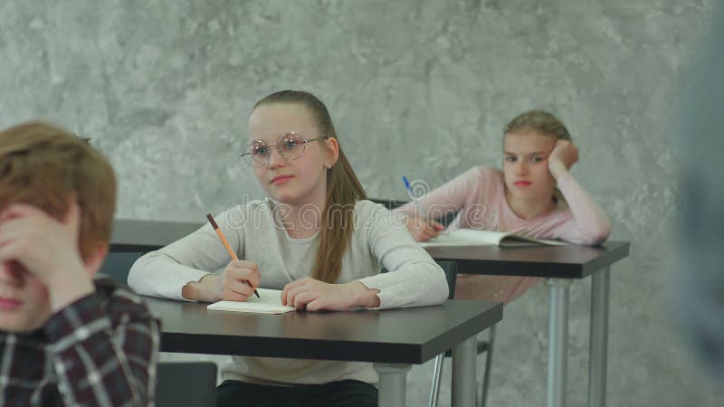 Studenti in uniforme scolastica che fanno un esame alla scrivania in una classe