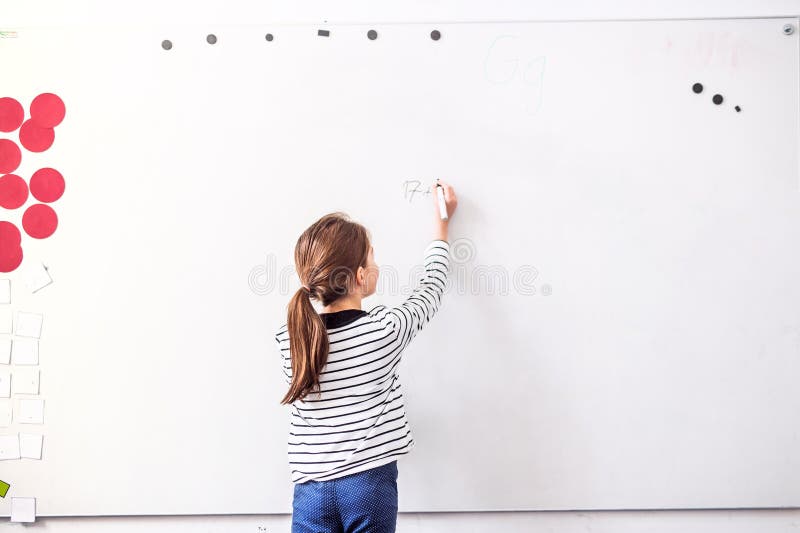 Studentin, die auf Whiteboard im Klassenzimmer schreibt. lizenzfreies stockbild