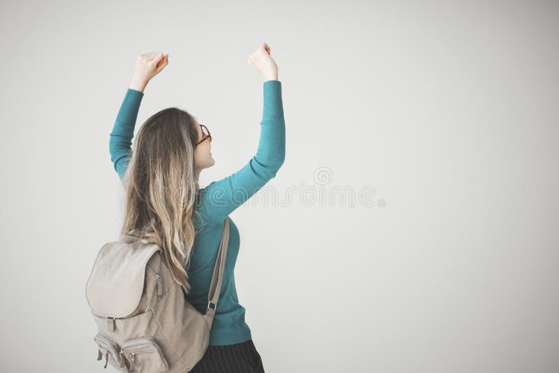 Studentinarme hoben mit Rucksack auf grauem Hintergrund an lizenzfreies stockbild Studentinarme hoben mit Rucksack auf grauem Hintergrund an lizenzfreies stockbild