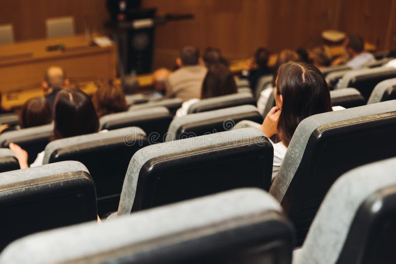Universitetsstudenter deltar i en lektion med professorn i auditoriet; publiken i konferenshallen lyssnar på föreläsaren under för arkivfoton