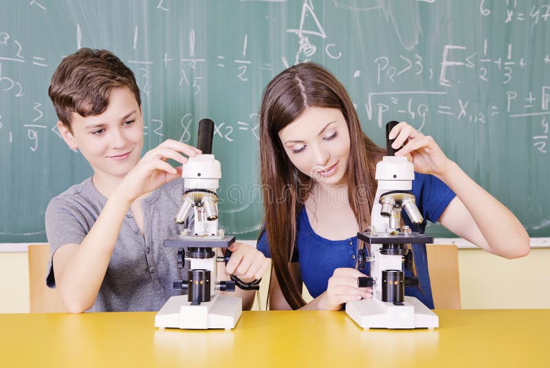 Students in science class using a microscope