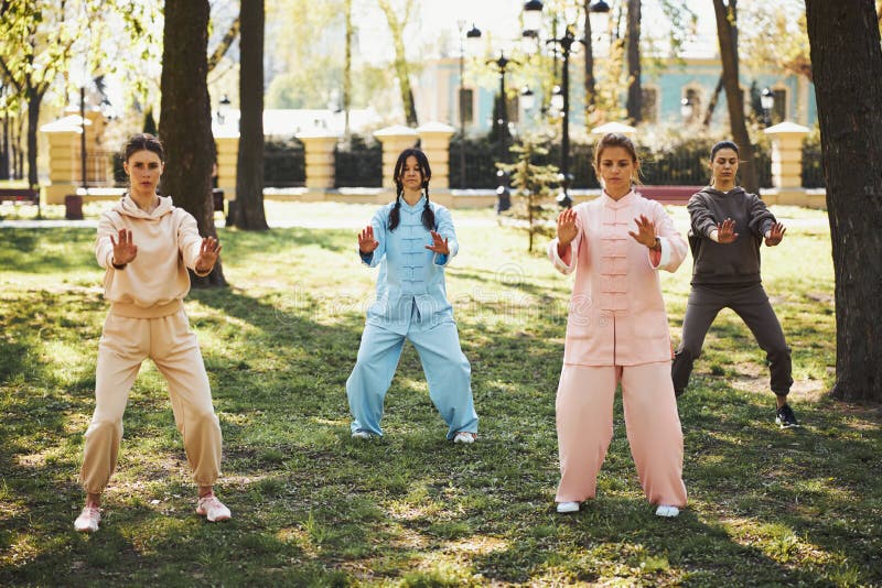 Women drawing out hands in front of themselves while staying with legs shoulder width apart during wushu training. Qigong class stock images, royalty-free photos and pictures