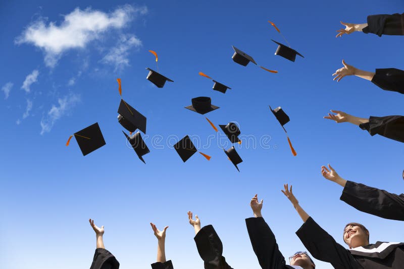 Students throwing graduation hats in the air celebrating with blue sky