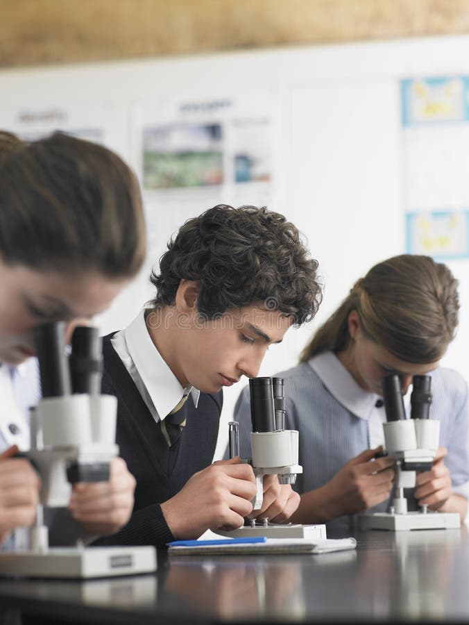 High school students using microscopes in laboratory