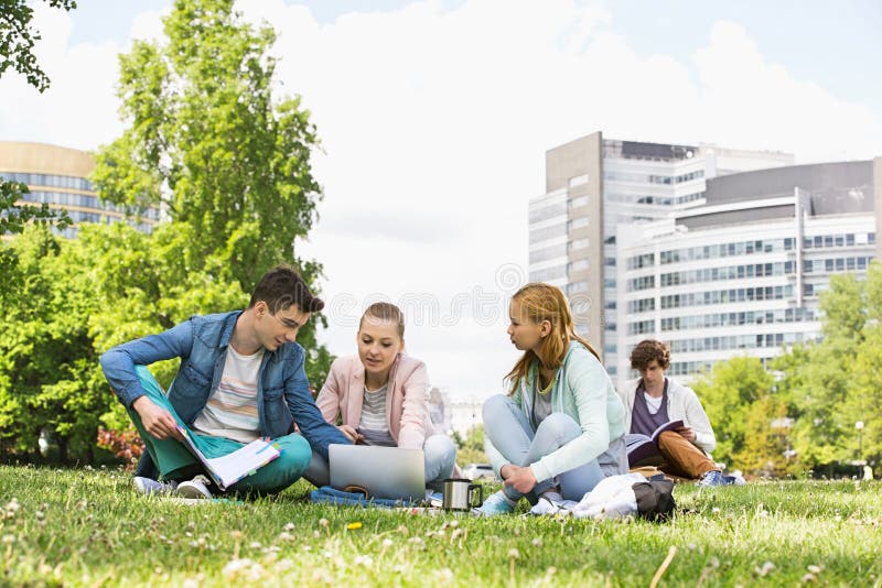 Studierende Collegefreunde bei der Anwendung des Laptops am Campus stockfotografie Studierende Collegefreunde bei der Anwendung des Laptops am Campus stockfotografie