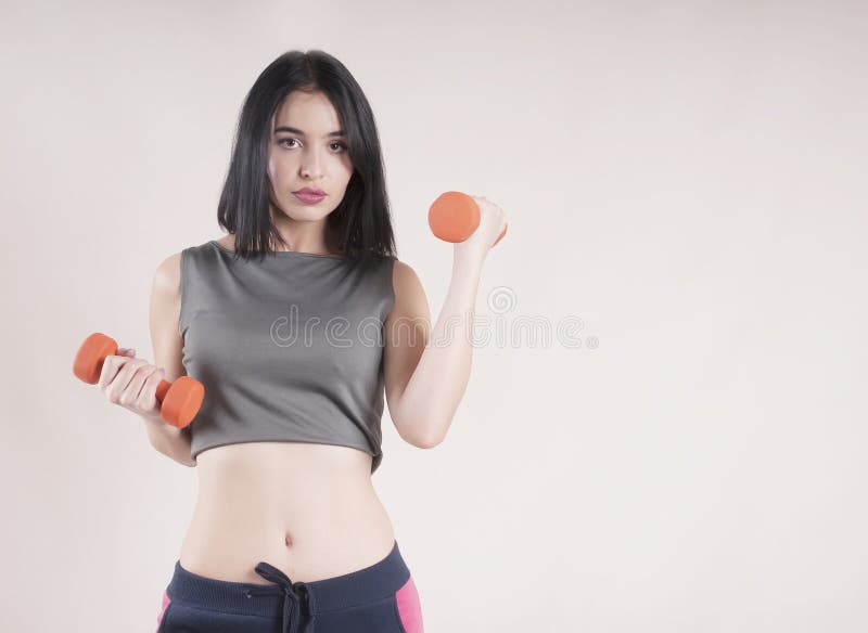 Studio concentré attrayant d'haltère de brune d'activité de belle fille de sports jolie images stock Studio concentré attrayant d'haltère de brune d'activité de belle fille de sports jolie images stock