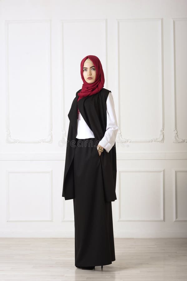 Studio photo of an oriental woman in a modern Muslim clothing, a scarf and a gold watch hand well