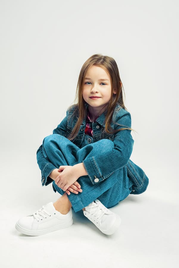 Studio portrait of a cute little girl. kids fashion child in denim pants and jacket and white sneakers royalty free stock image Studio portrait of a cute little girl. kids fashion child in denim pants and jacket and white sneakers royalty free stock image