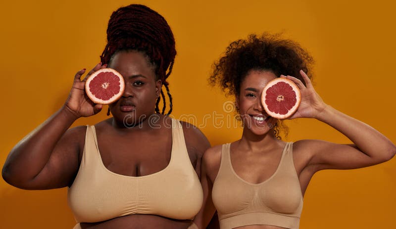 Studio-Porträt von zwei jungen afrikanischen amerikanischen Frauen in Unterwäsche mit Blick auf die Kamera mit der Hälfte der saft stockbilder