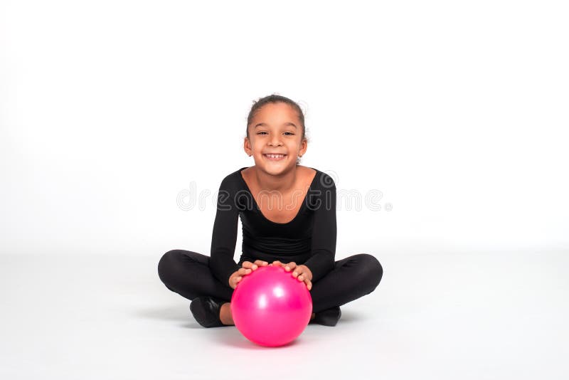 Studio shot of attractive little gymnast girl of mulatto with long braid of frizzy wearing black legends and a bathing suit