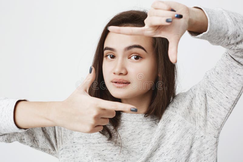 Studio shot of good-looking european model, lifting her eyebrow and showing frame gesture over white background. Girl stock photo Studio shot of good-looking european model, lifting her eyebrow and showing frame gesture over white background. Girl stock photo