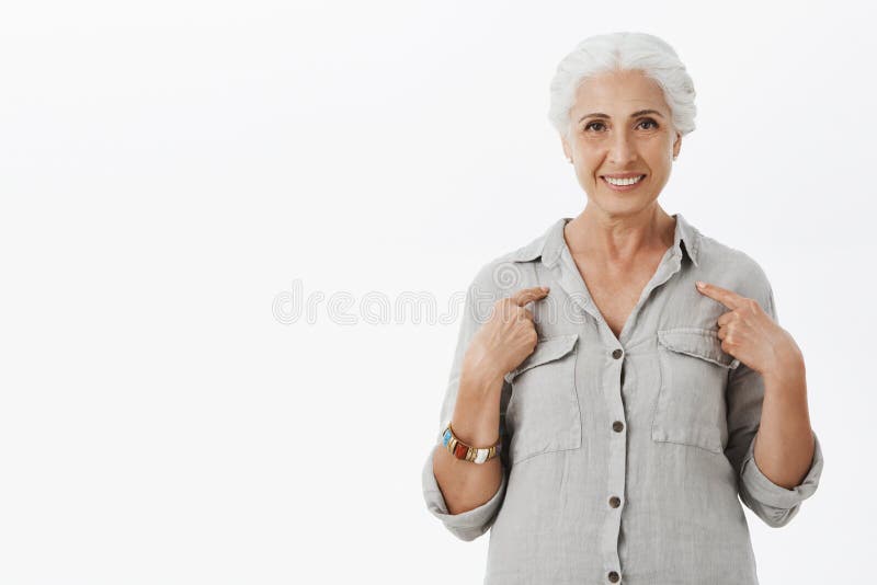 Studio shot of kind and cute elderly mother with gray hair pointing at herself with pleased and self-assured smile stock photo Studio shot of kind and cute elderly mother with gray hair pointing at herself with pleased and self-assured smile stock photo