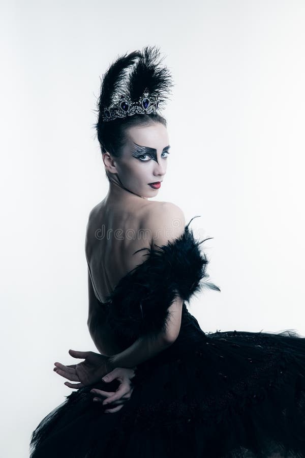 Studio shot of young ballerina wearing black tutu, stage dress and bright make-up posing isolated on white studio